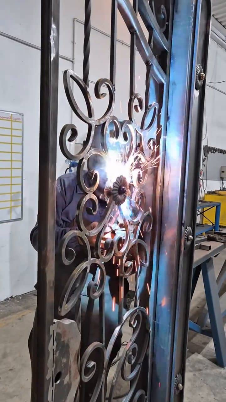 Shower of sparks while welding a rosette onto the scrolls of a garden gate, in the workshop