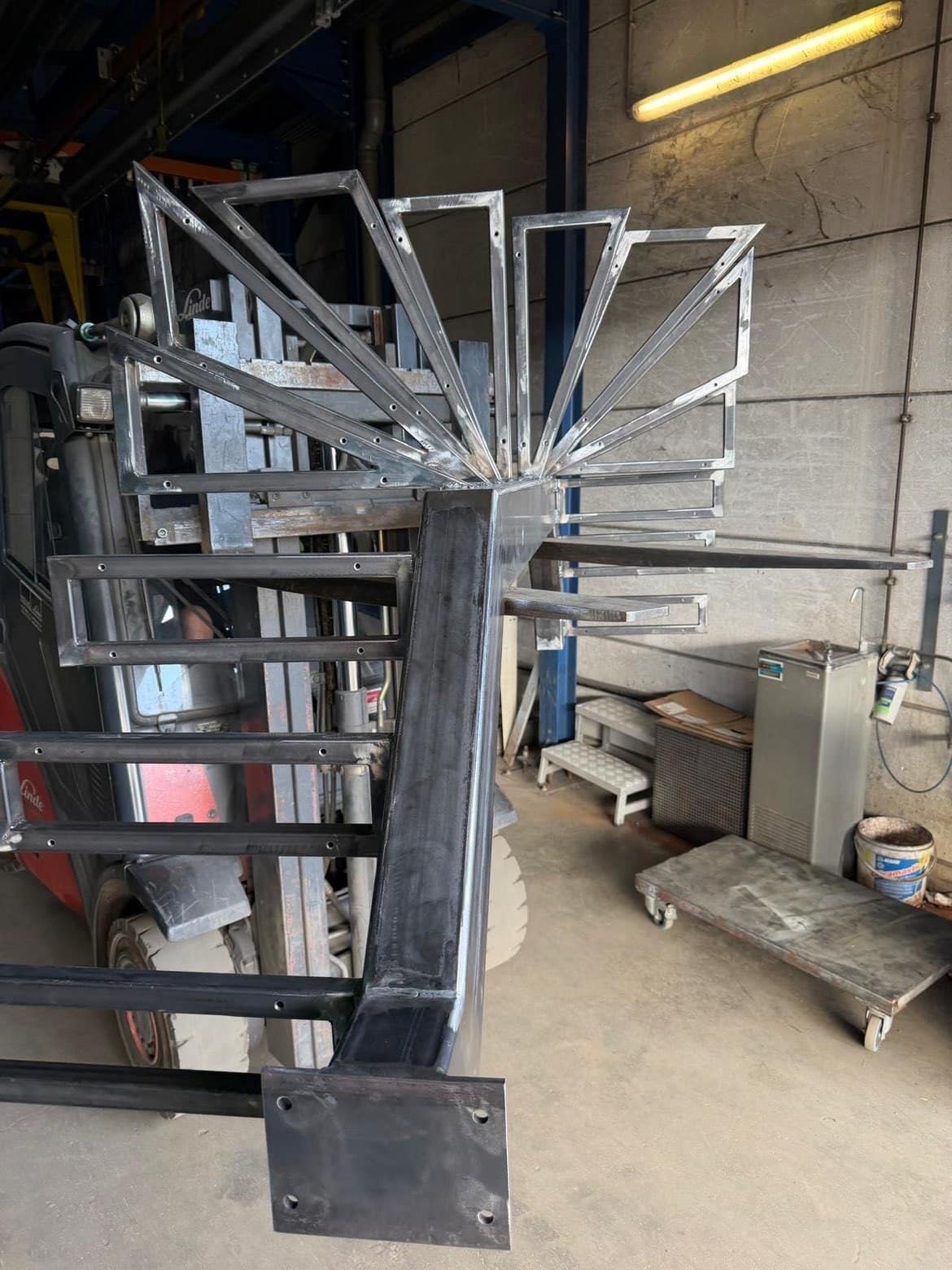 Structuur van een draaitrap in ruw staal in het atelier, centrale trapboom en gelaste tredesteunen, vóór de afwerking